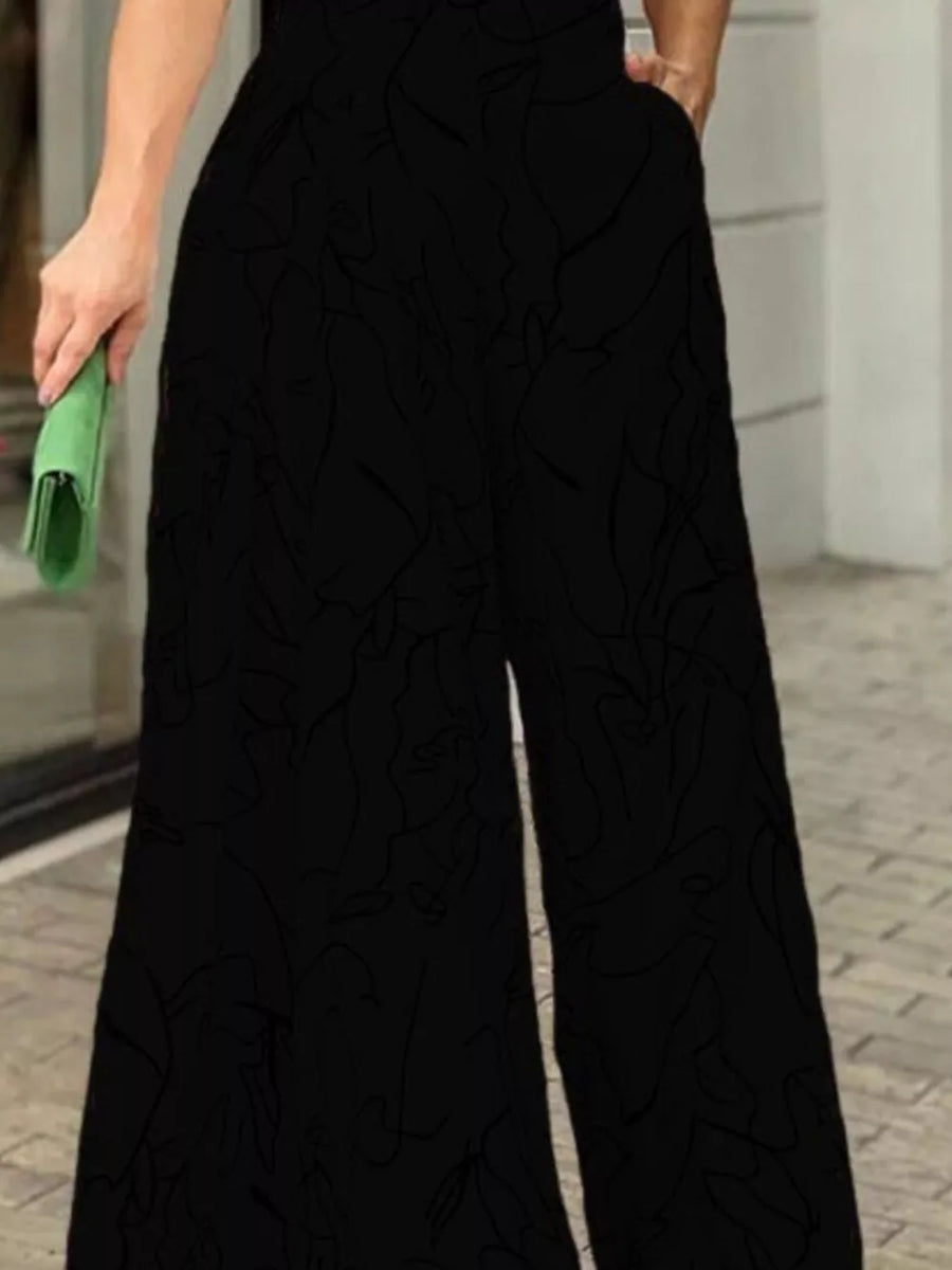 Black halter neck romper with abstract line print and wide legs.