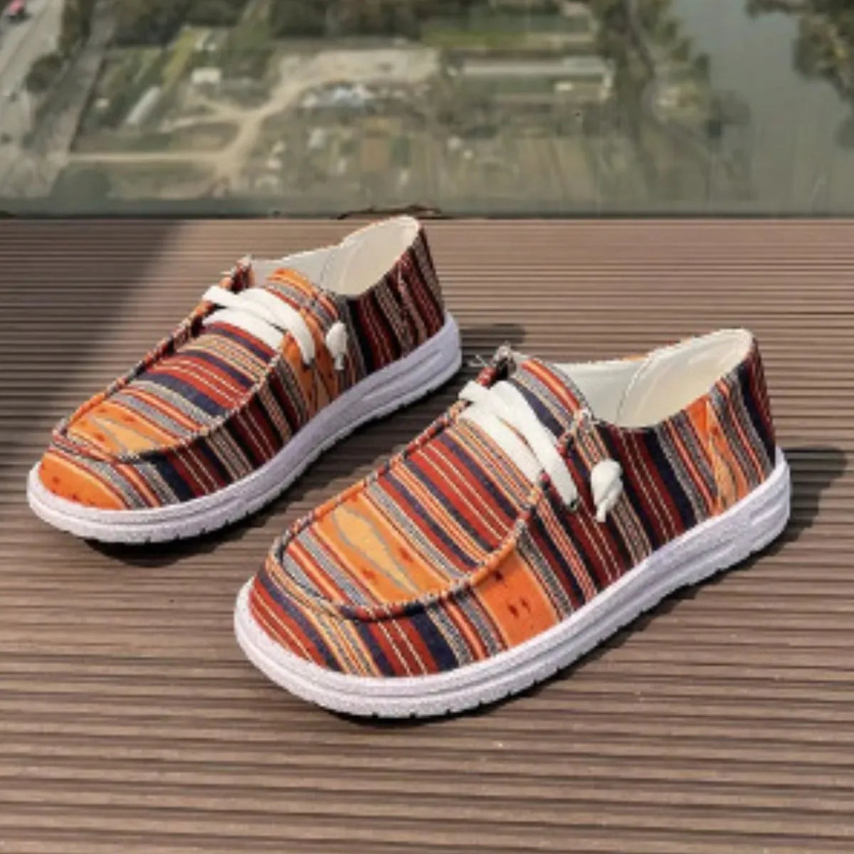 Linen-blend boat shoes with white laces and a striped pattern in orange, navy, and red.