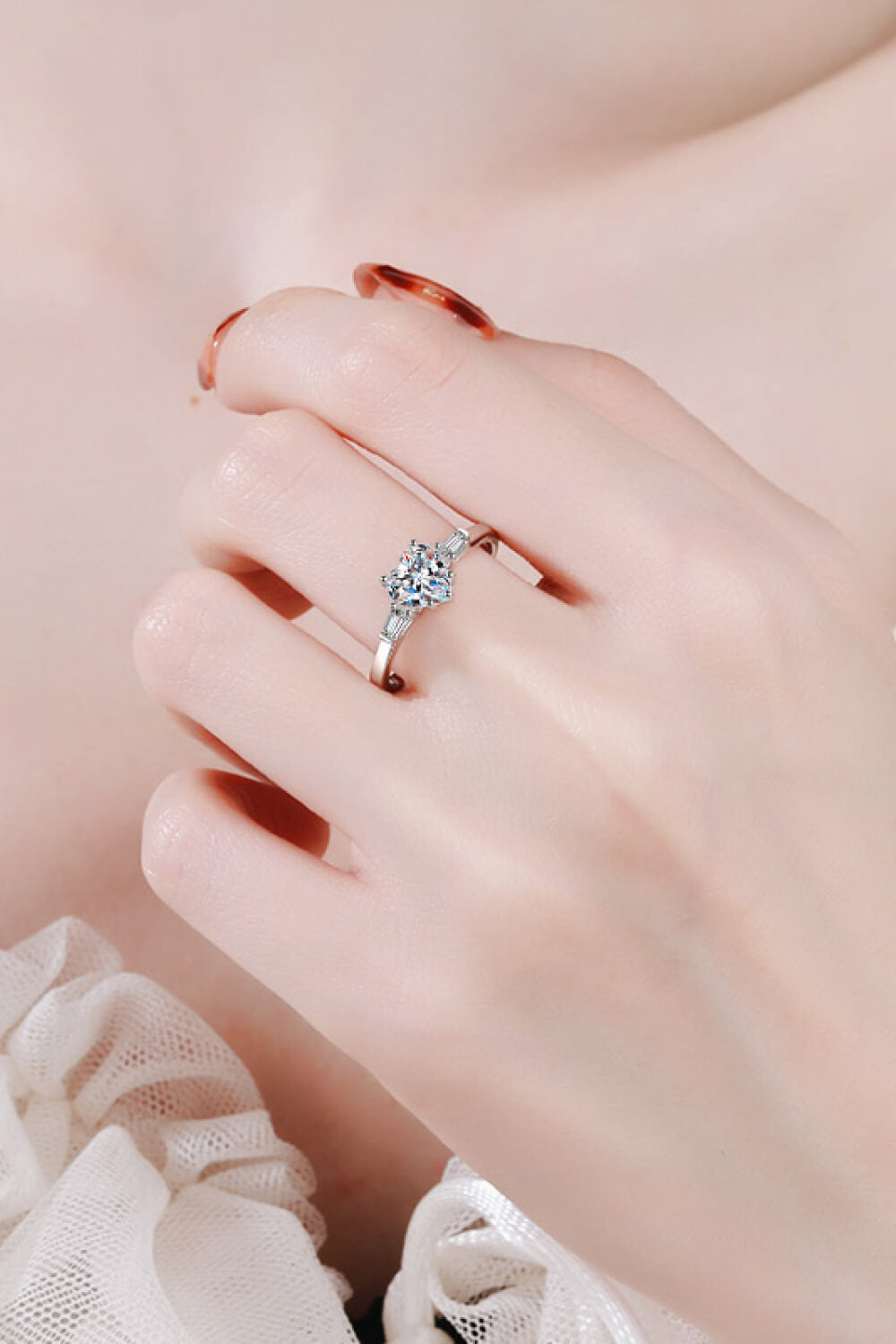 Silver ring with heart-cut moissanite and baguette accents on a hand.
