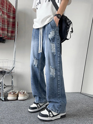 Oversized distressed wide-leg jeans in light blue denim with drawstring waist.