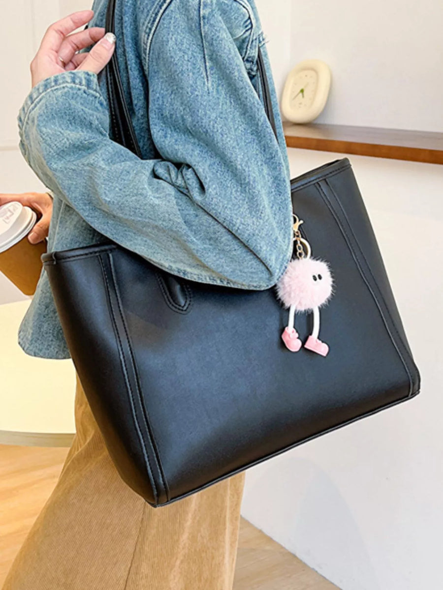 Black PU leather tote bag with a cute pink pompom charm and a denim jacket.