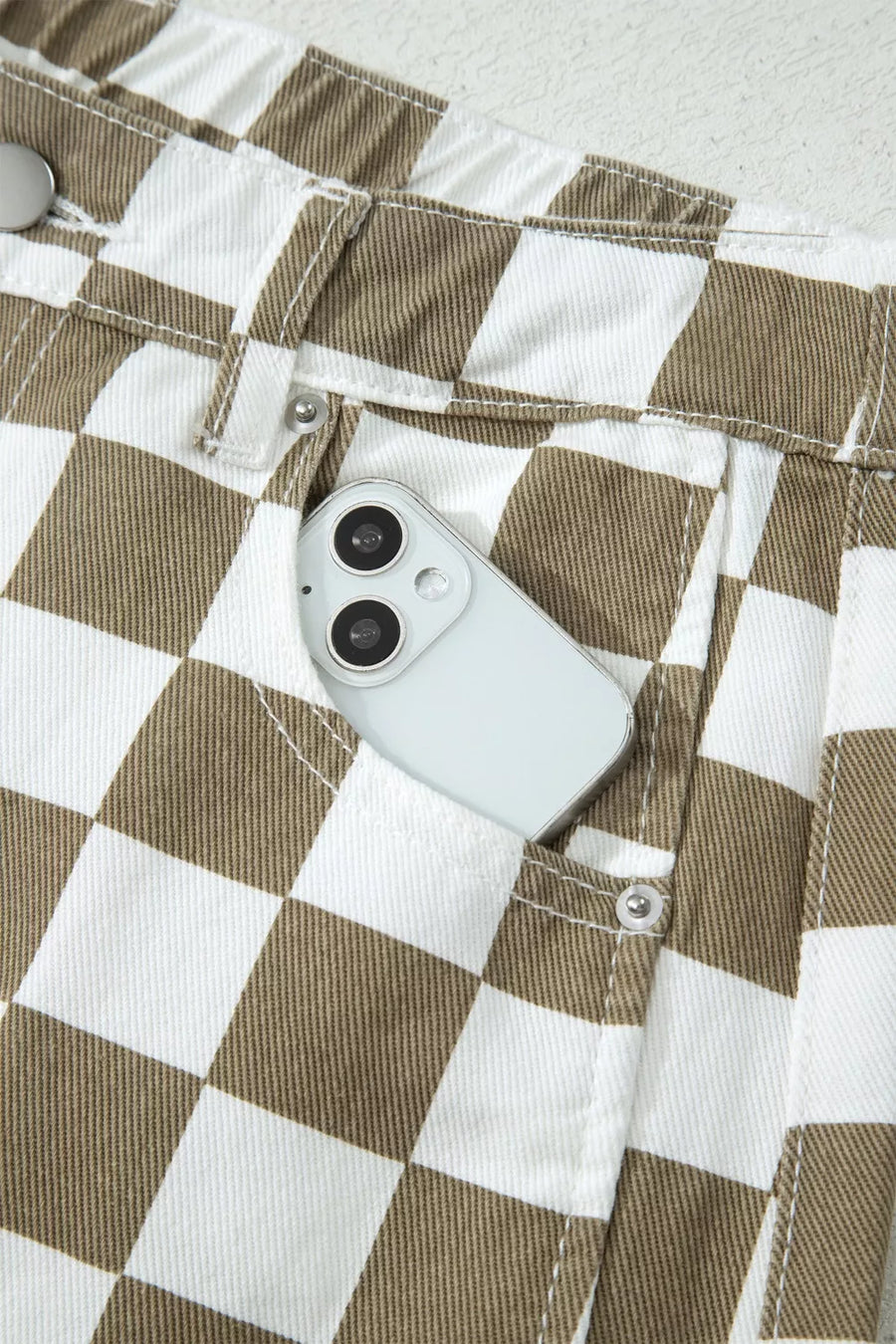 Chic checkered denim barrel pants in brown and white with a phone in the pocket.