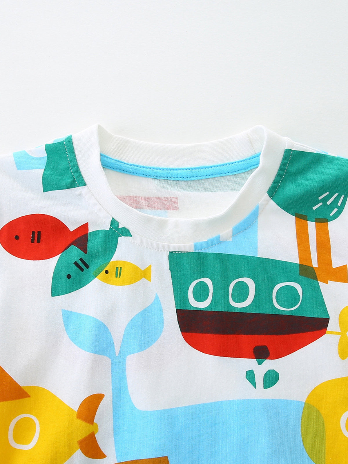 White cotton toddler t-shirt with a colorful marine print featuring boats and fish.