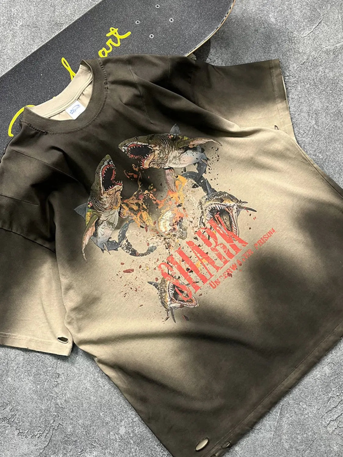 Distressed khaki t-shirt with a bold shark graphic and distressed details.