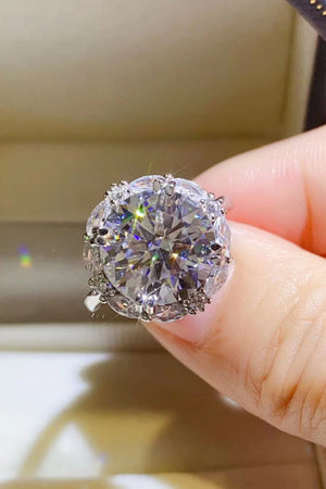 Silver moissanite statement ring with large round-cut center stone and halo of smaller stones.