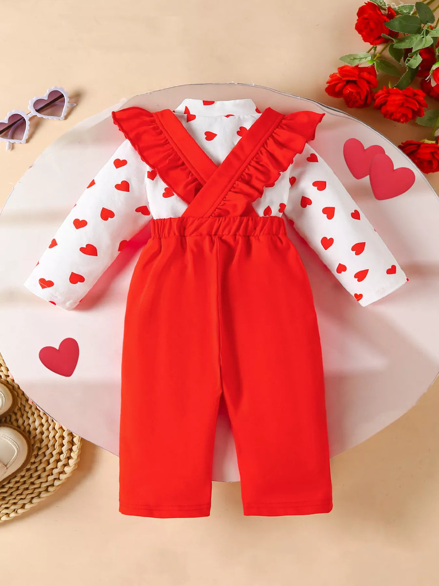 Baby girl's red suspender pants and white heart print long sleeve top set with ruffled straps.