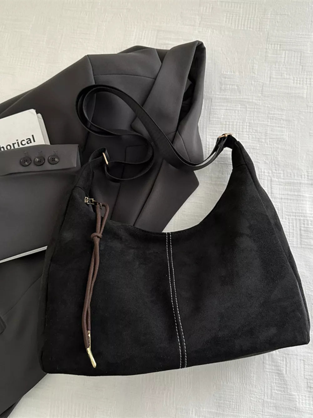Black suede crossbody bag with adjustable strap and contrast stitching