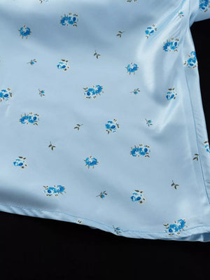 Light blue satin top with a blue floral print and short sleeves.