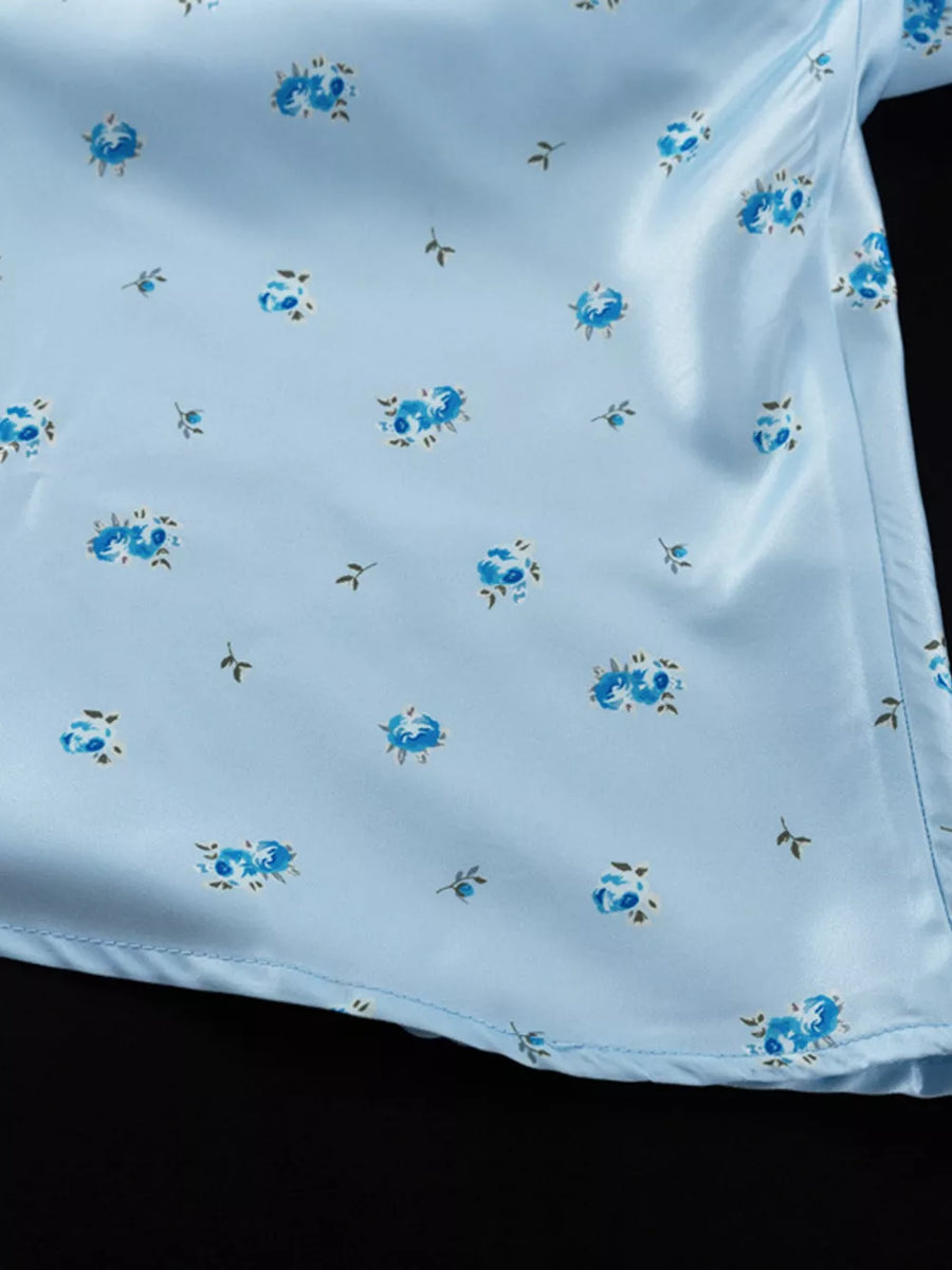 Light blue satin top with a blue floral print and short sleeves.