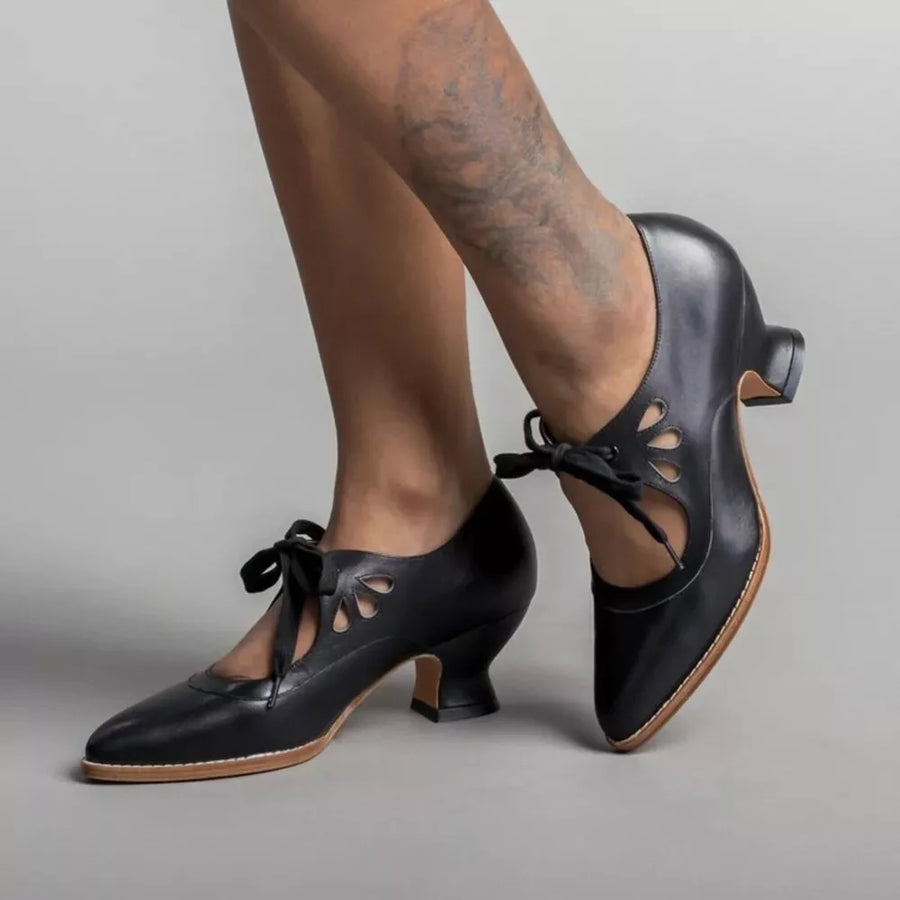 Black leather pointed toe pumps with cutouts and tie laces.