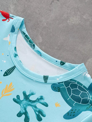 Light blue t-shirt with allover ocean print featuring turtles, fish, and coral.