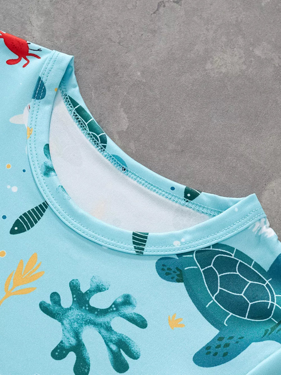 Light blue t-shirt with allover ocean print featuring turtles, fish, and coral.