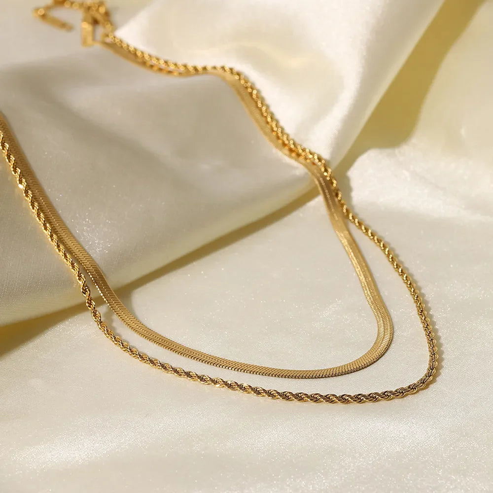 Gold serpentine and rope chain necklaces layered on satin fabric