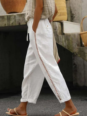 White relaxed cropped pants with hollow out trim detail and drawstring waist.