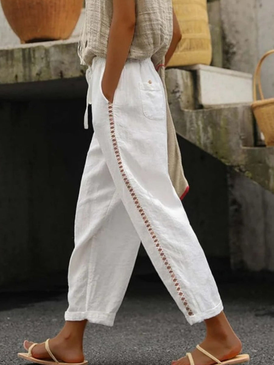 White relaxed cropped pants with hollow out trim detail and drawstring waist.