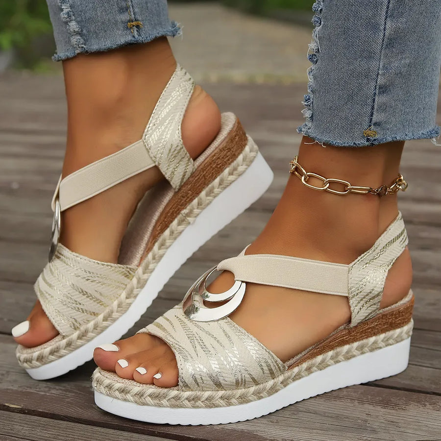 Beige espadrille wedges with metallic accents and a ring detail.
