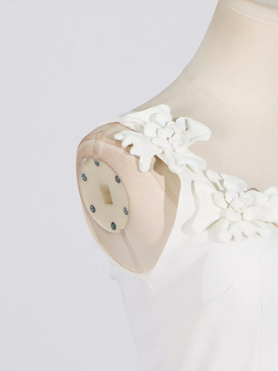 White dress with delicate floral shoulder embellishments and sheer straps.