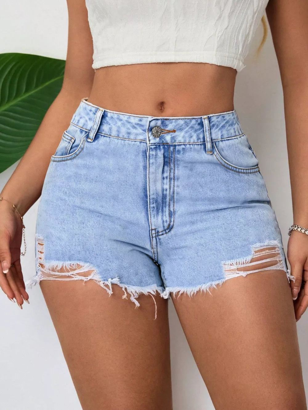 Light wash denim shorts with high waist, distressed rips, and frayed hem.