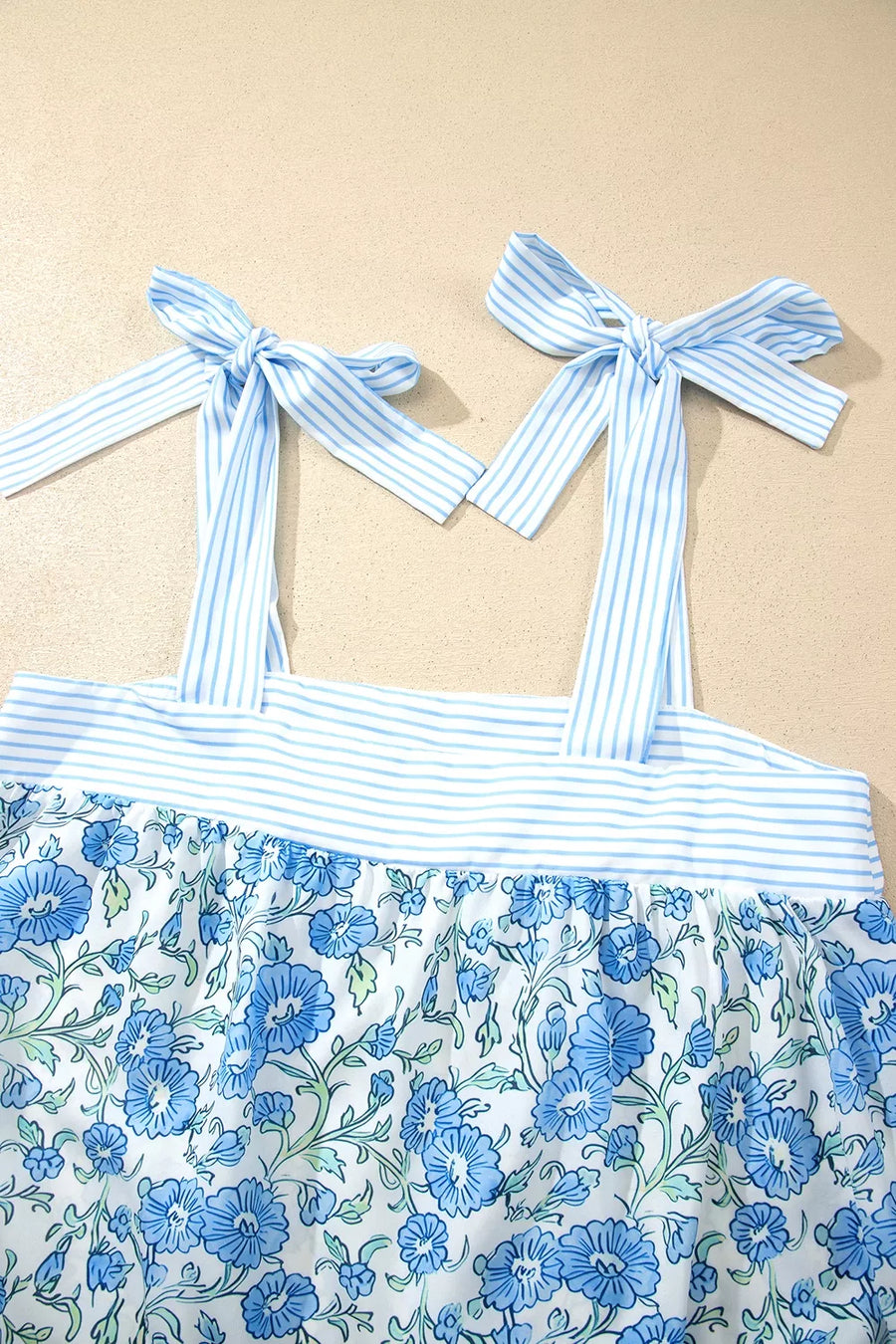 Blue floral print cami top with adjustable tie straps and striped trim, part of a loungewear set.
