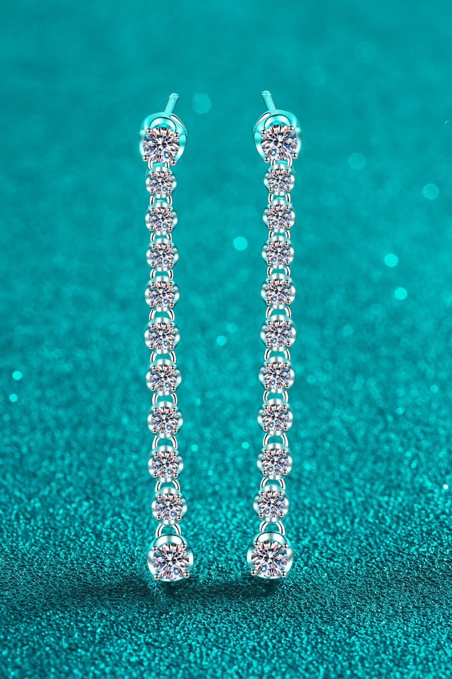 Silver linear drop earrings with multiple round moissanite stones cascading down.