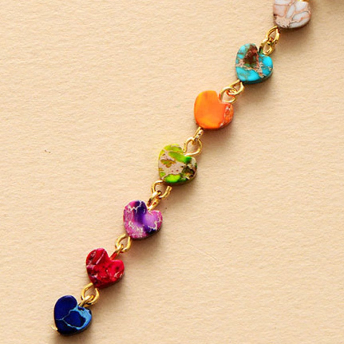 Rainbow heart cascade necklace with gold chain and multicolor stone hearts.