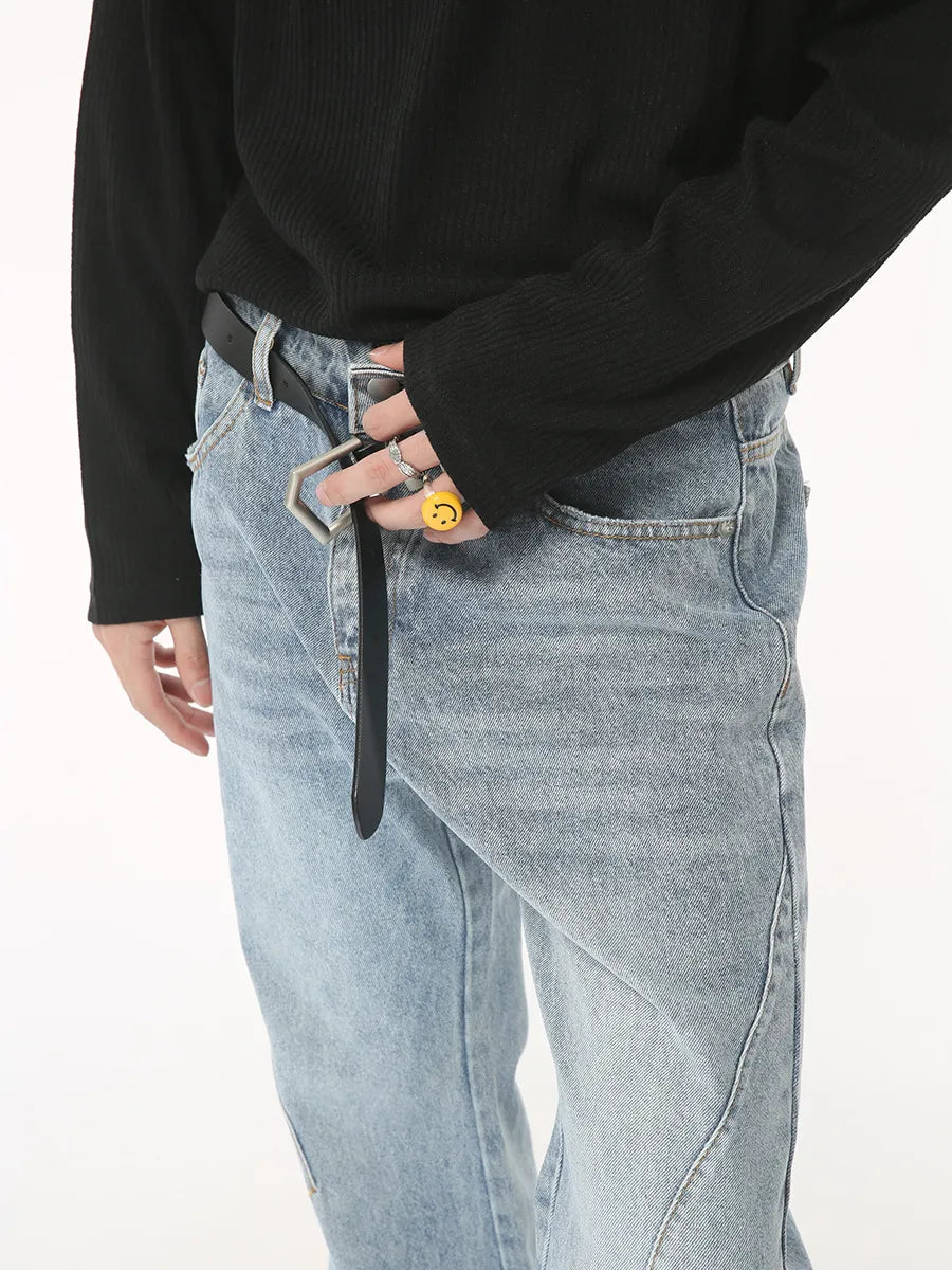 Flared denim jeans in medium wash with sculpted seam detail and a black belt.
