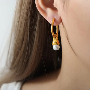 Gold oval hoop earrings with a pearl drop detail.