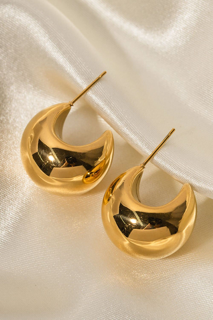 Gold sculptural crescent hoop earrings with a polished finish.