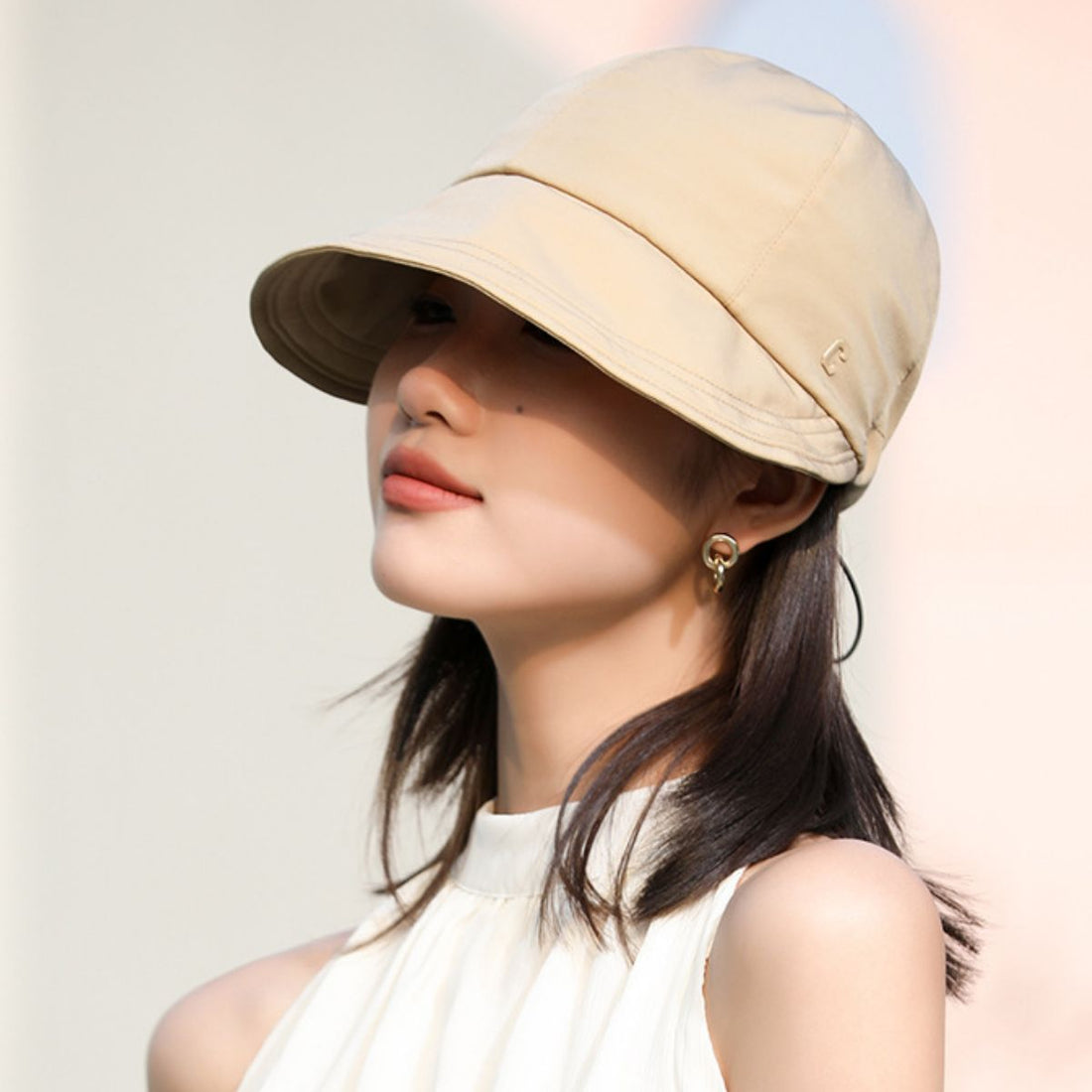 Khaki bucket hat with adjustable strap and subtle logo detail, offering UV protection.