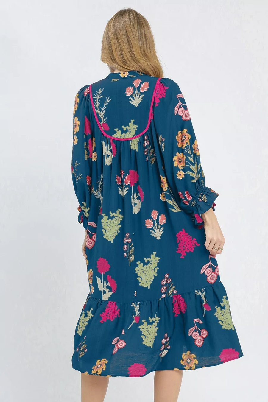 Maxi dress in teal with a floral print, pink trim, long sleeves, and tiered hem