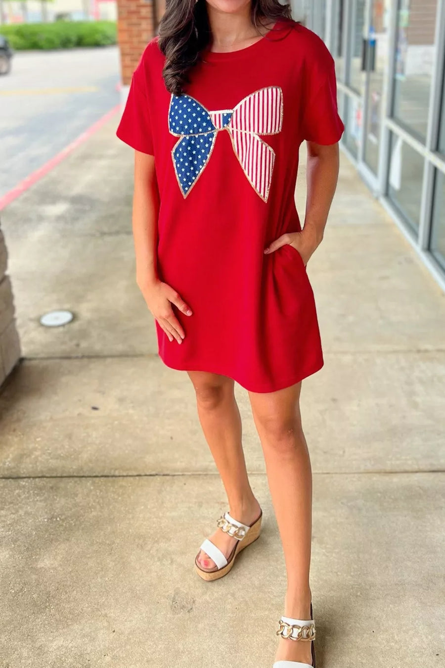 Red cotton mini dress with stars and stripes bow graphic, short sleeves, and pockets.