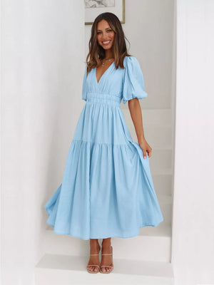 Pastel blue midi dress with puff sleeves, V-neck, and tiered skirt.