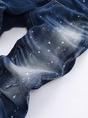 Men's dark blue distressed slim-fit jeans with white paint splatters and subtle rips.