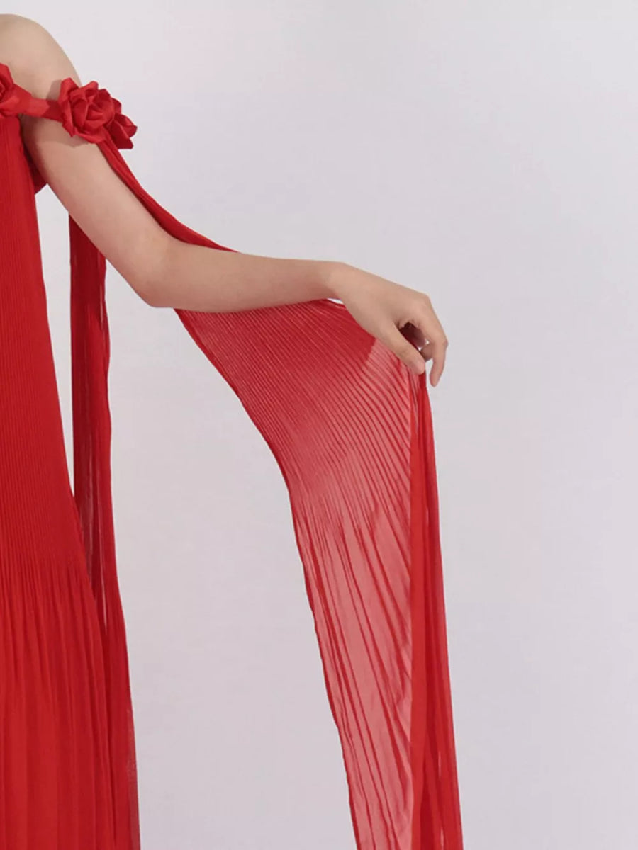 Red off-shoulder maxi dress with pleated fabric and floral appliques on sleeves.