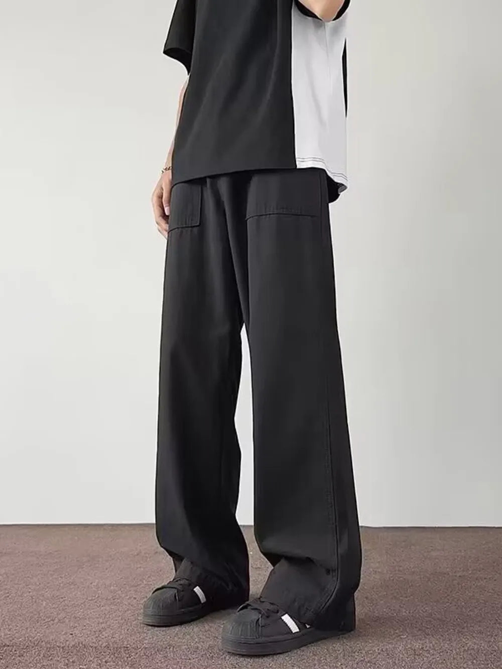 Black casual wide-leg cargo pants with flap pockets on a man.