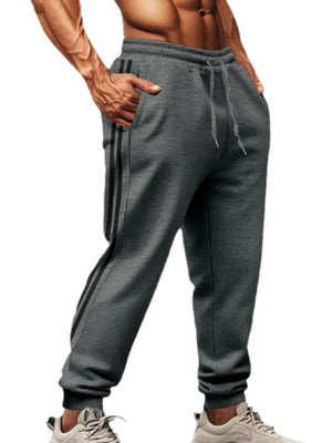Gray joggers with black athletic stripes down the leg, drawstring waist, and cuffed ankles.