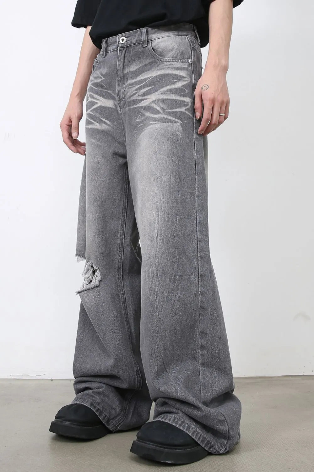 Distressed dark gray wide-leg denim jeans with a ripped knee detail.