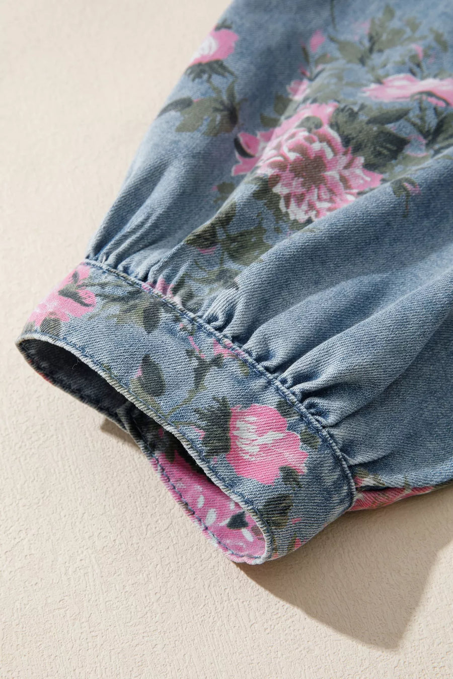 Denim button-up shirt with a floral print on the cuff and sleeve.