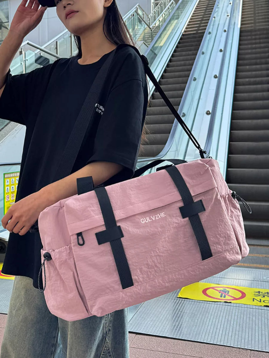 Pink duffel bag with adjustable strap and black accents