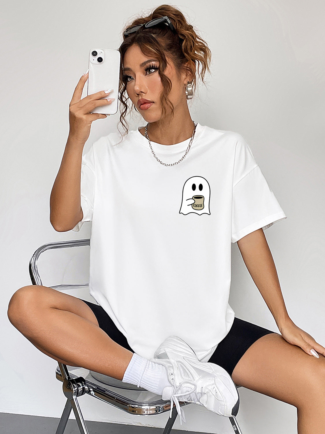 White graphic t-shirt with a cute ghost holding a coffee cup on the chest.