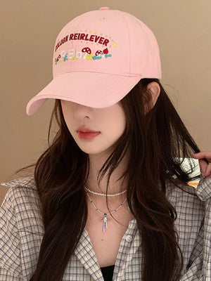 Blush pink baseball cap with playful mushroom embroidery and text detail.