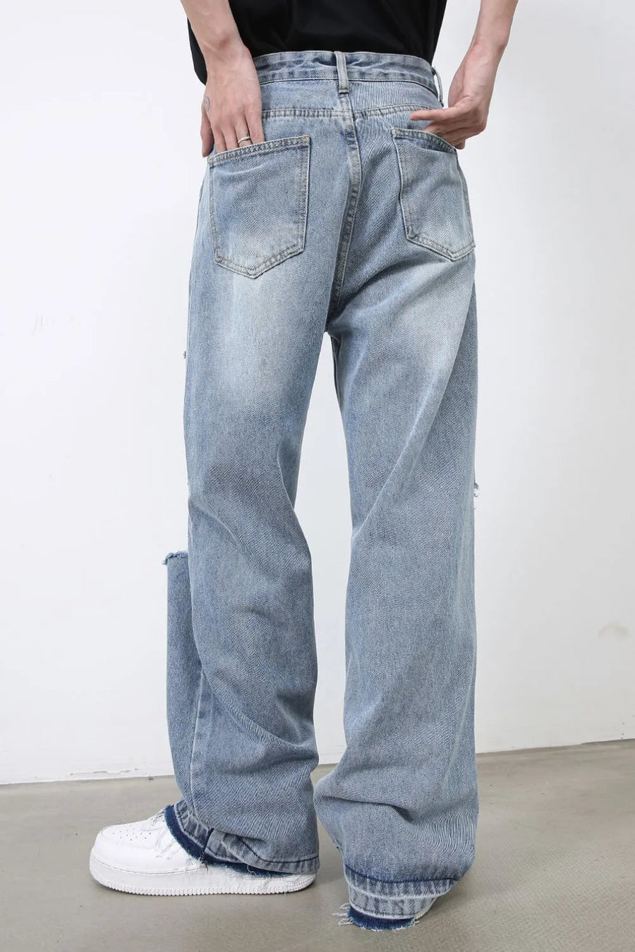 Light blue distressed wide-leg jeans with raw hem detail and ripped accents.