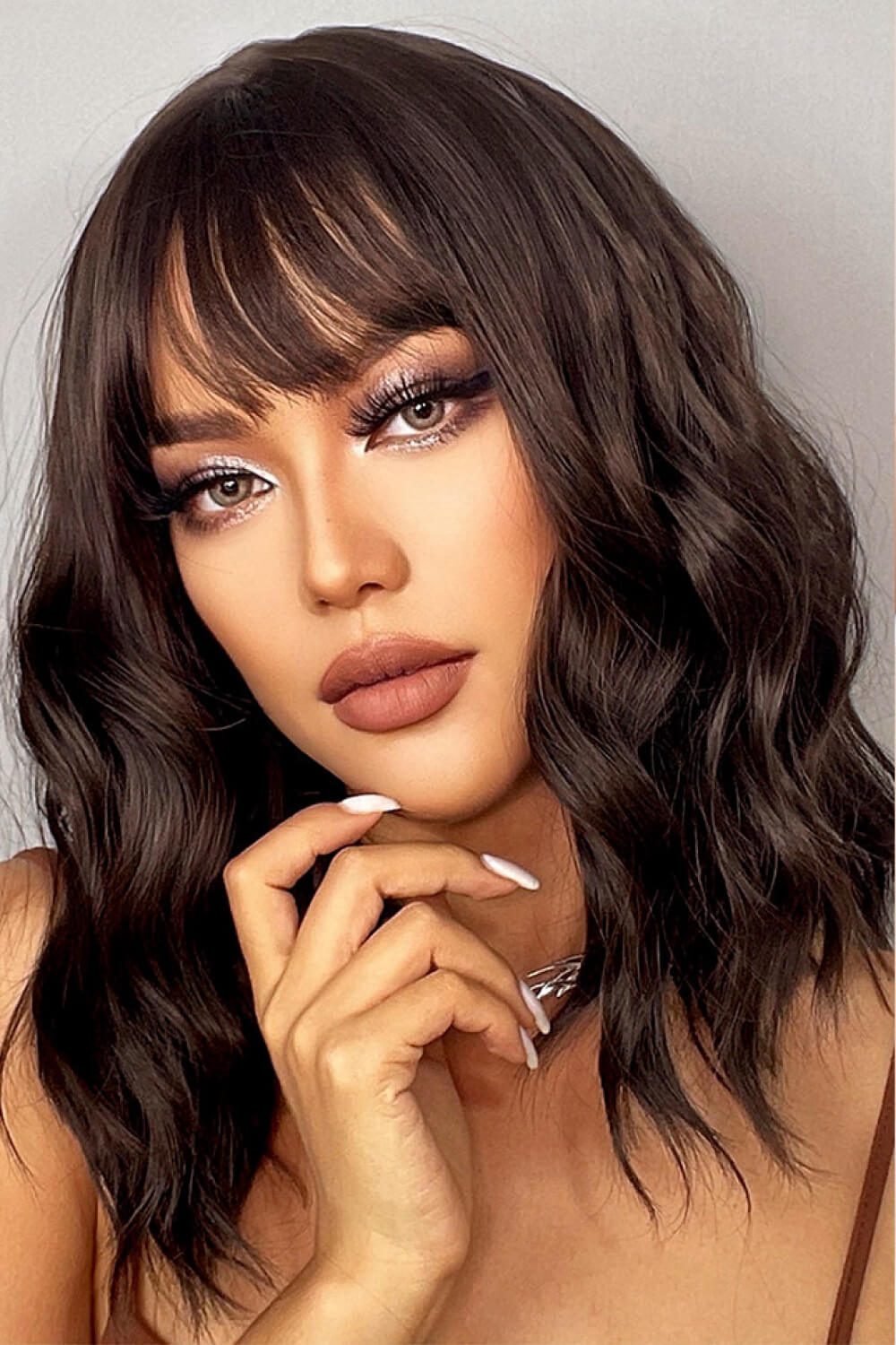 Textured black bob wig with fringe, styled in loose waves.