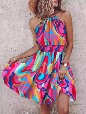 Bohemian halter mini dress with abstract print, smocked waist, and tiered skirt.