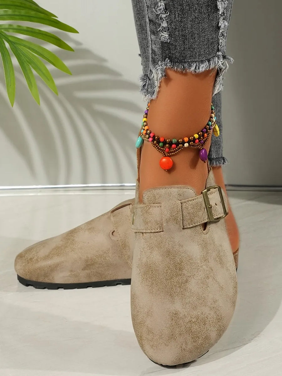 Beige textured suede mules with buckle detail and cork sole.
