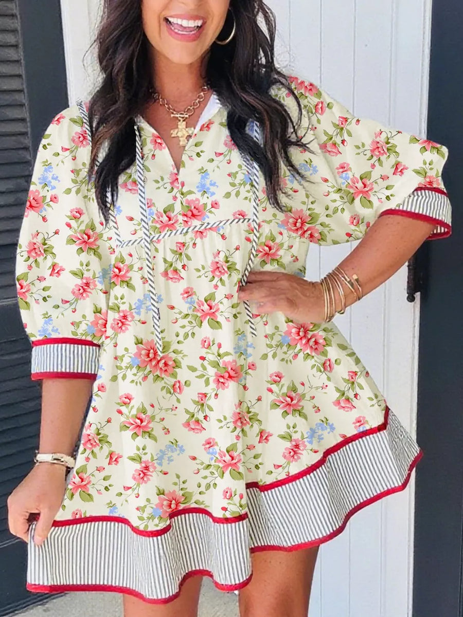 Floral print cotton dress with puff sleeves, tie neck, and striped trim.