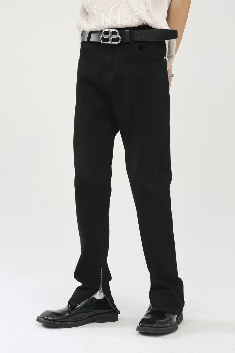 Black denim trousers with zip hem detail and a silver zipper pull.