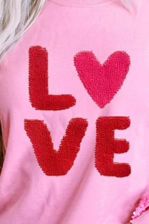 Pink sweatshirt with red sequin "LOVE" appliqué and sequin sleeve detail.