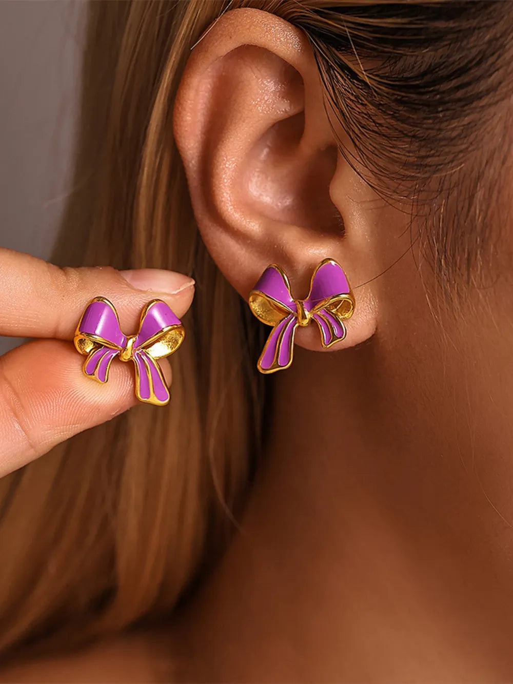 Vivid Violet enamel bow stud earrings with gold detailing on ear