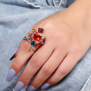 Multi-layered gold-plated ring with colorful crystals on a hand.
